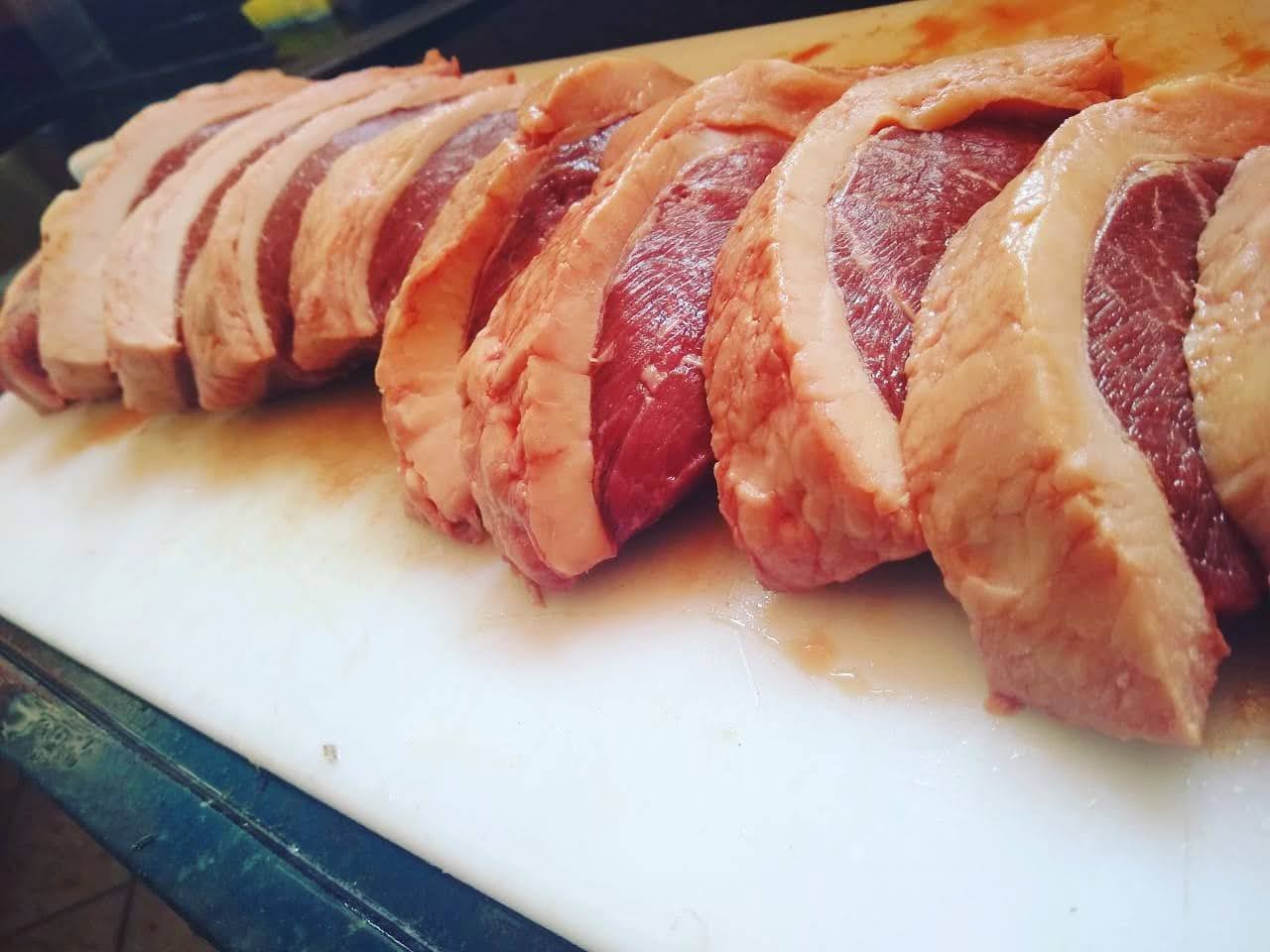 Cortes de picanha crua alinhados em tábua de corte
