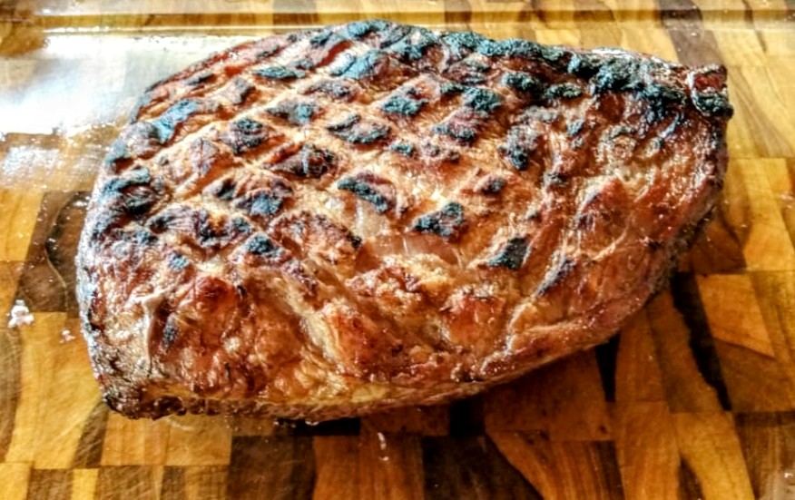 Picanha grelhada com marcas da grelha sobre tábua de madeira